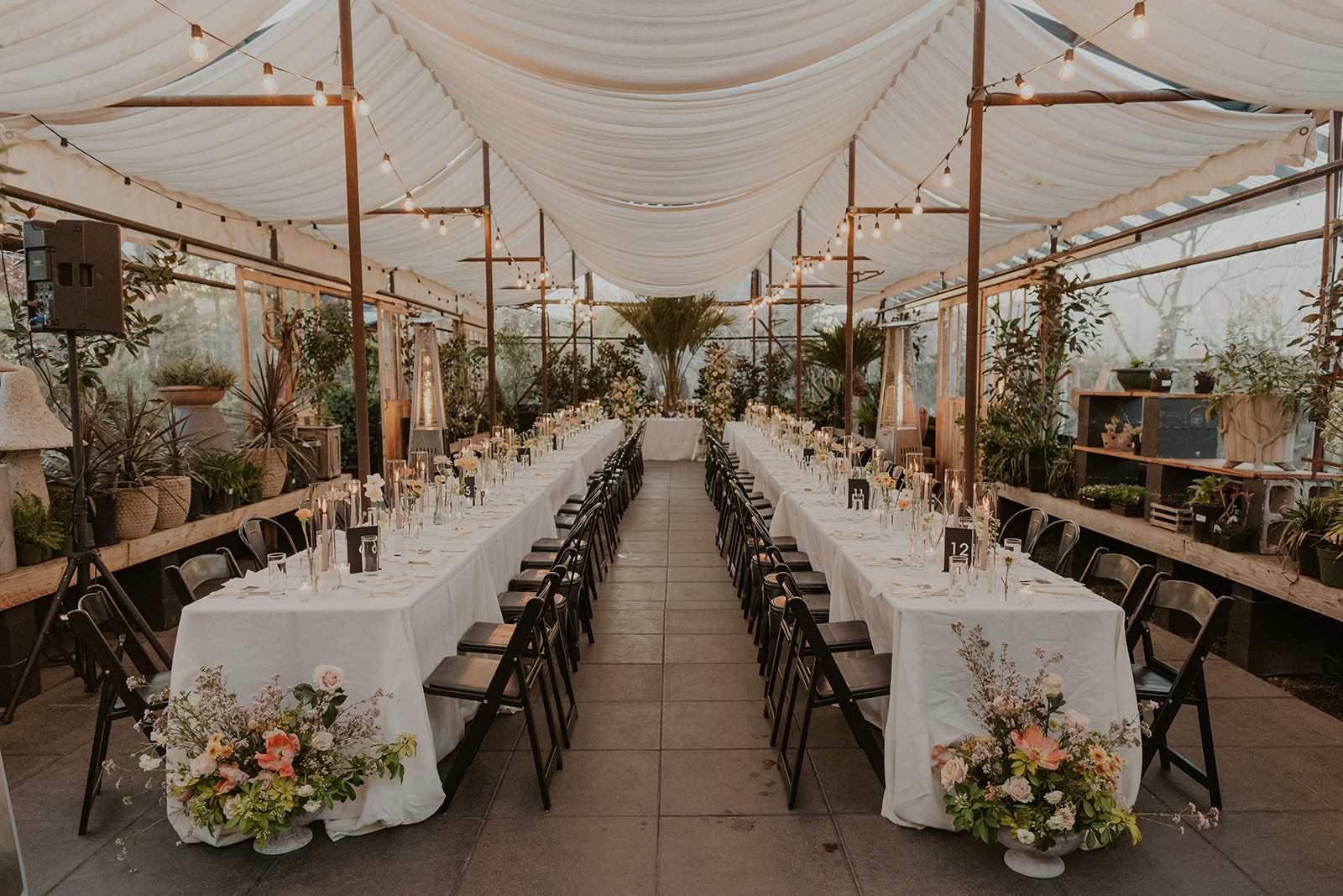 Outdoor wedding reception in Oregon with 2 long dining tables with white linen and black chairs at a Portland Oregon Greenhouse Venue
